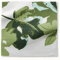 A bedroom covered in peter Dunham fig leaf pattern - on the walls and a matching lampshade. the headboard is green with a vintage pillow and gray bedspread.